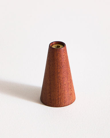 Warm, reddish brown wooden cone-shaped incense holder by Ryuji Mitani on a graybackground