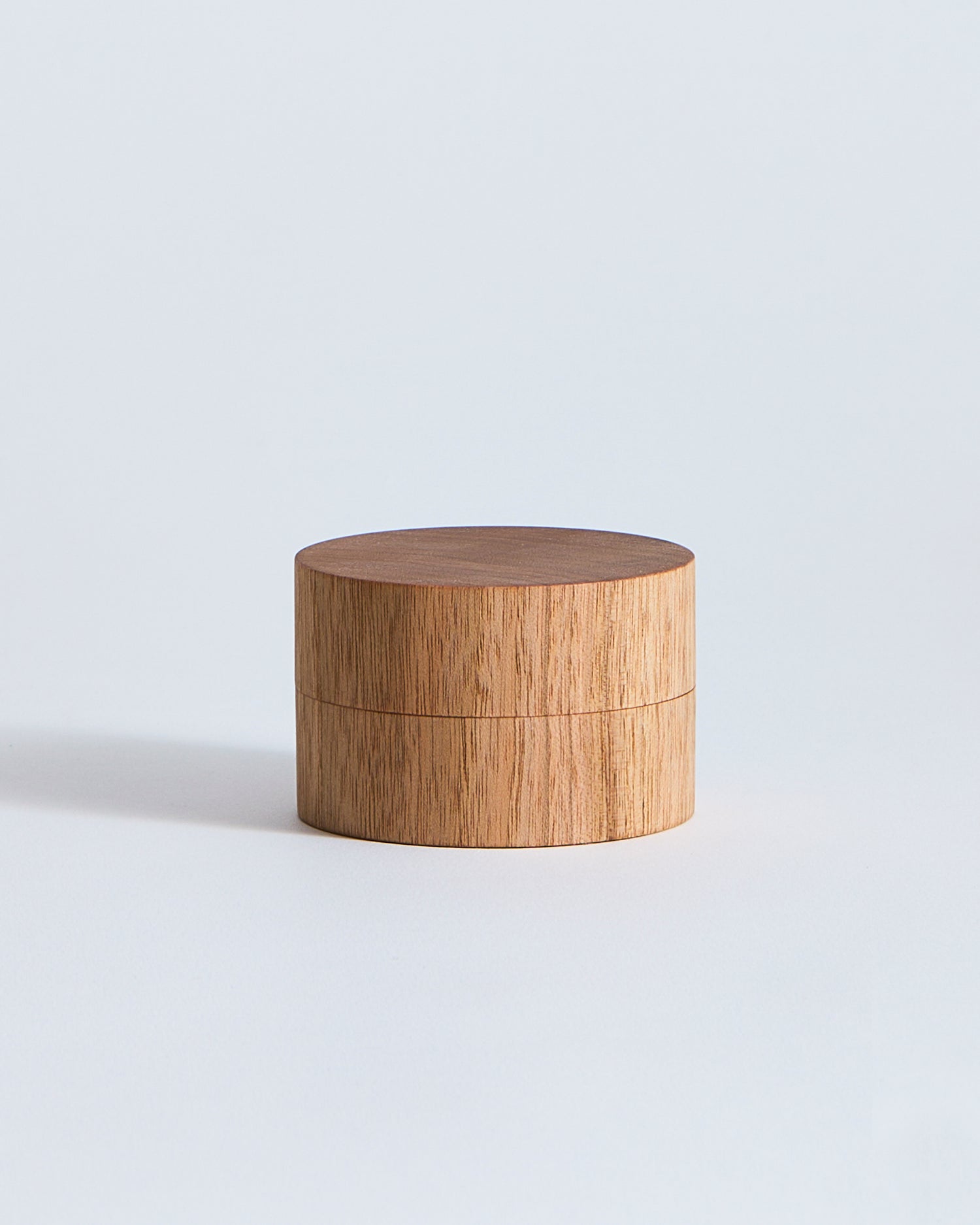 Wooden cylindrical container by Ryuji Mitani on a light gray background