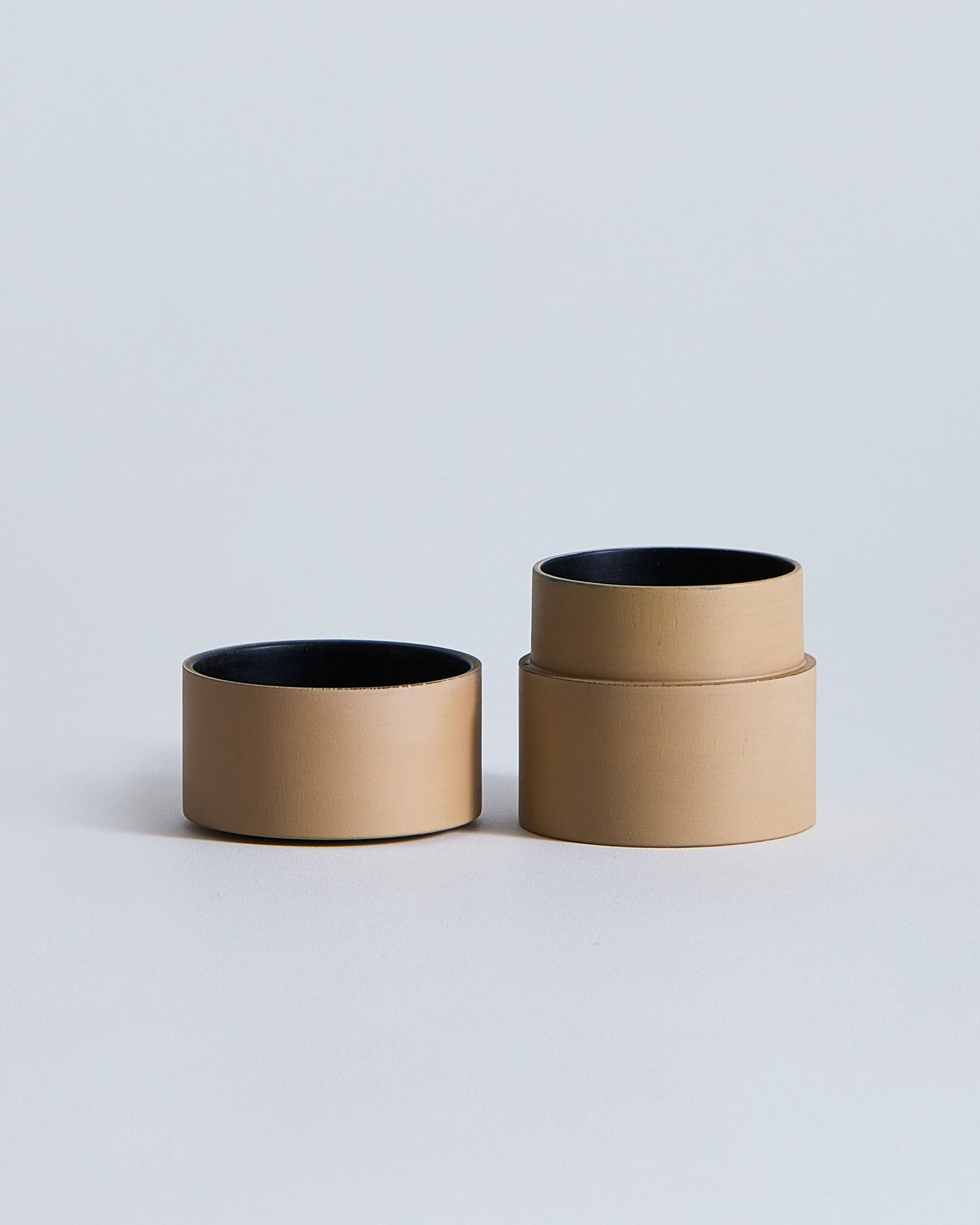 Opened beige container with lid, showing the black interior, by Ryuji Mitani on a light gray background