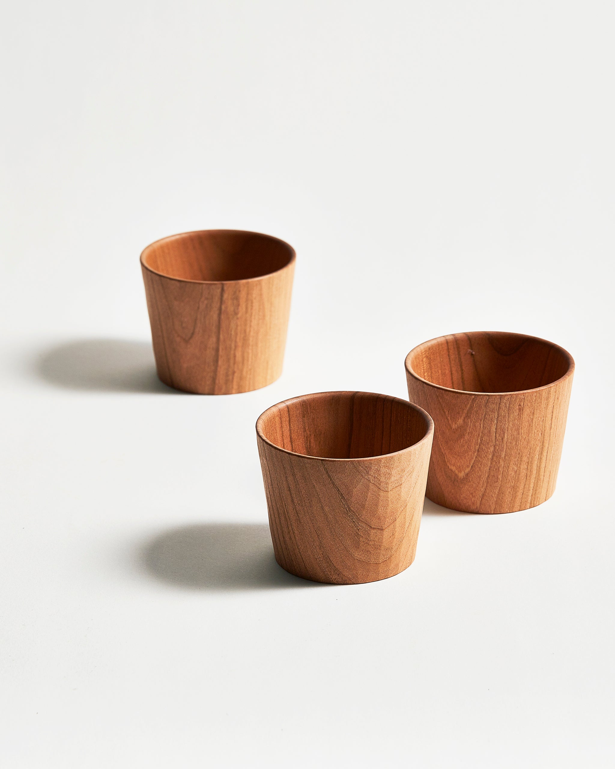 Three wooden cups by Ryuji Mitani on a light gray background