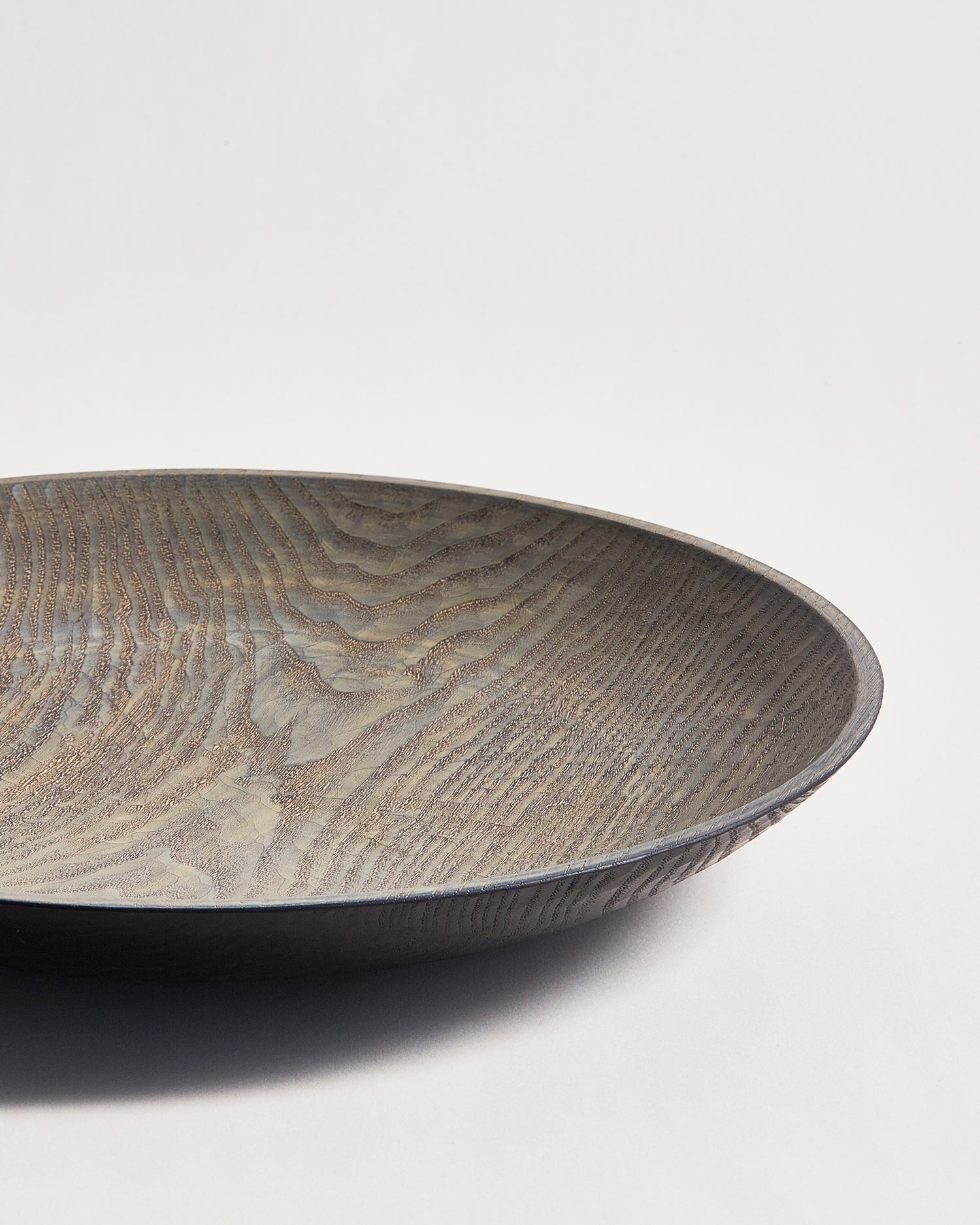 Close-up RIght corner of wooden bowl with a textured surface by Ryuji Mitani on a gray background