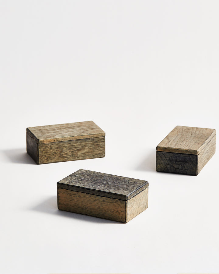 Angled view of 3 scattered Usuzumi Thin Lid Boxes by Ryuji Mitani against white-gray background.