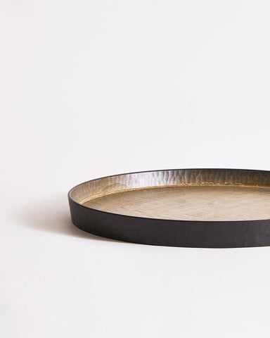 Round wooden tray with black rim and beige interior by Ryuiji Mitani on a gray background