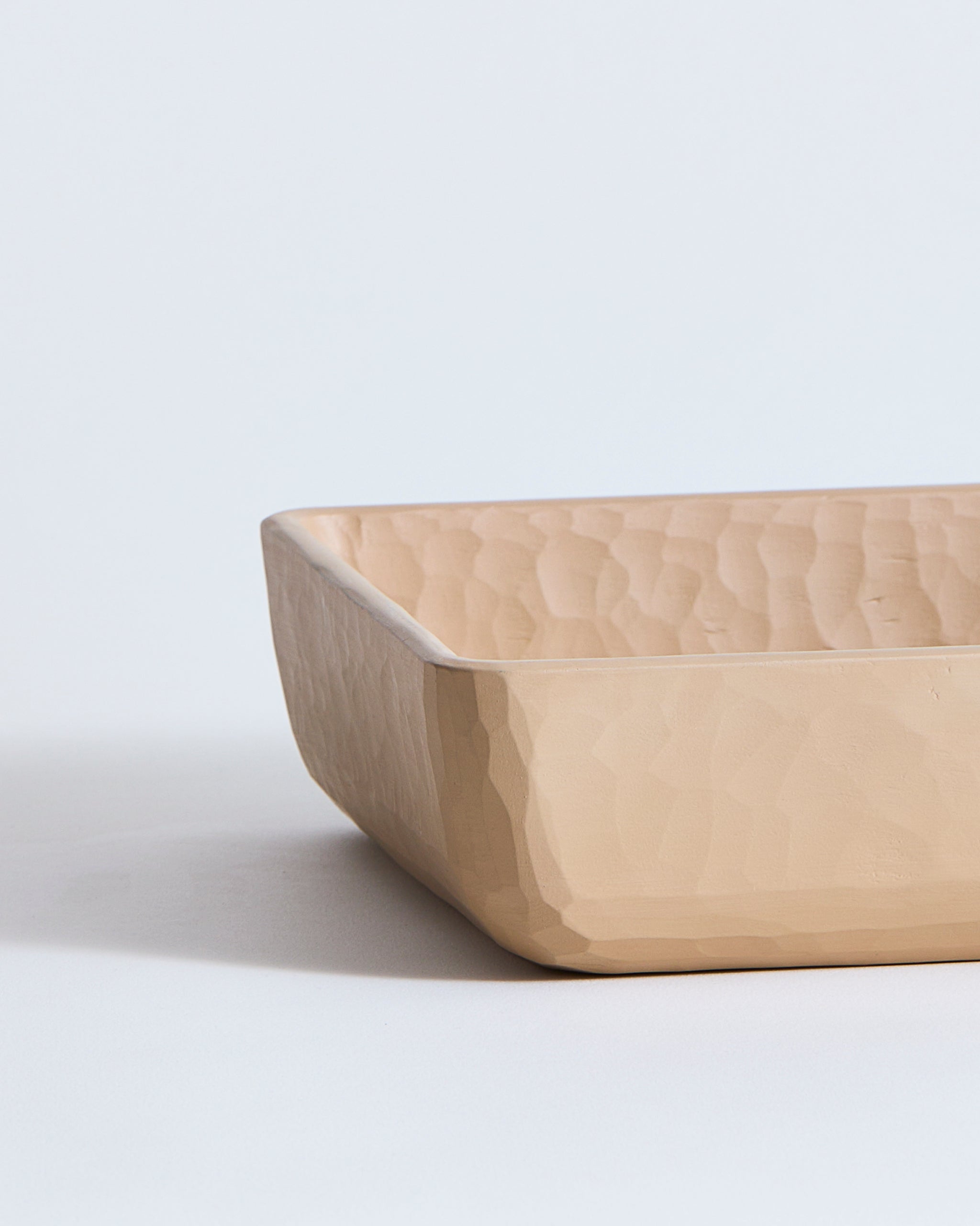 Beveled edge of a beige wooden square dish by Ryuji Mitani on a light gray background