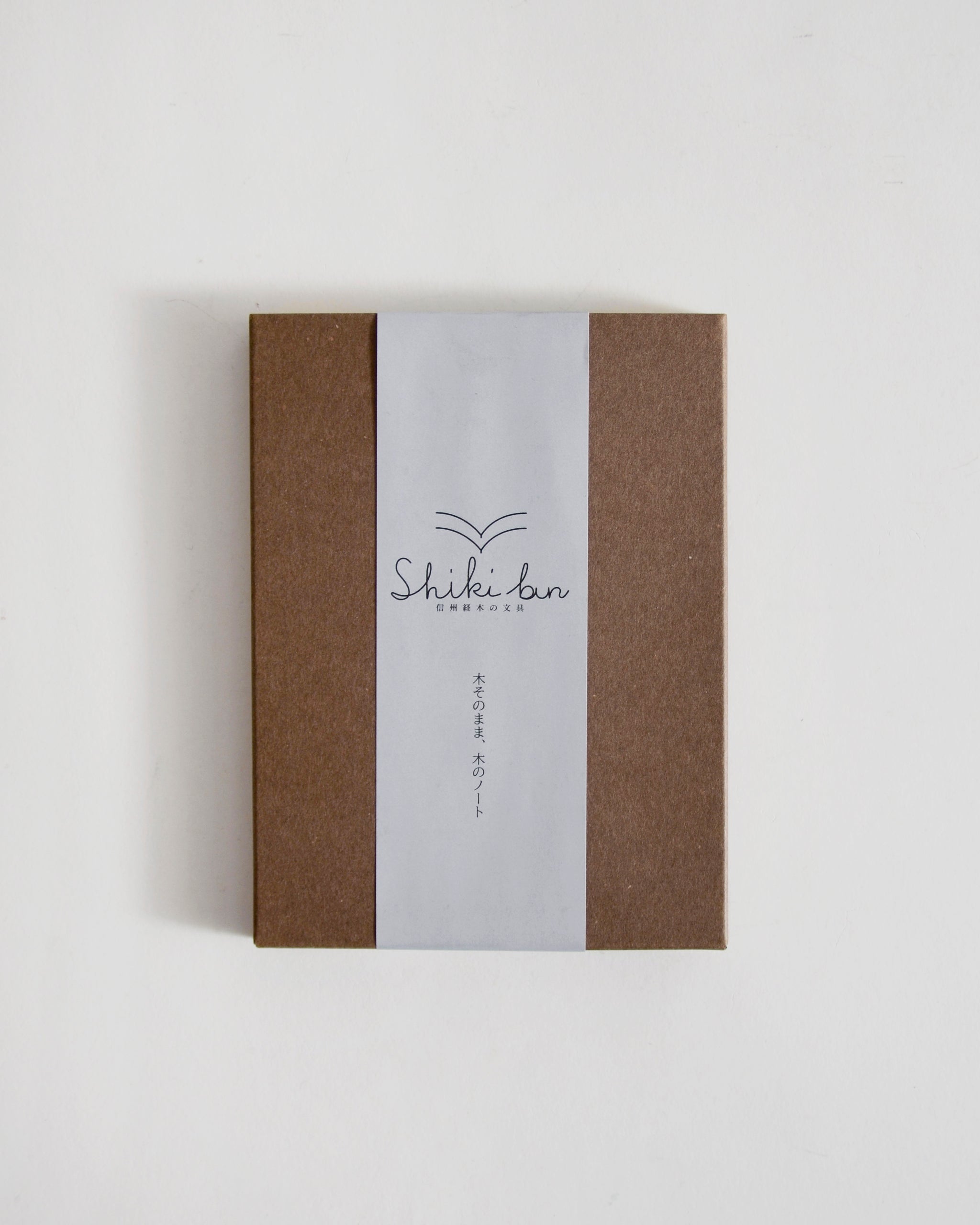 Brown outer packaging of notebook with a white label featuring 'Shiki-bun' on a light gray background
