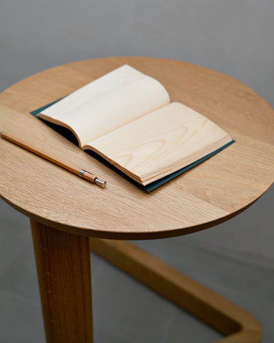 Open notebook by Shiki-bun and pen on a wooden side table with a gray background