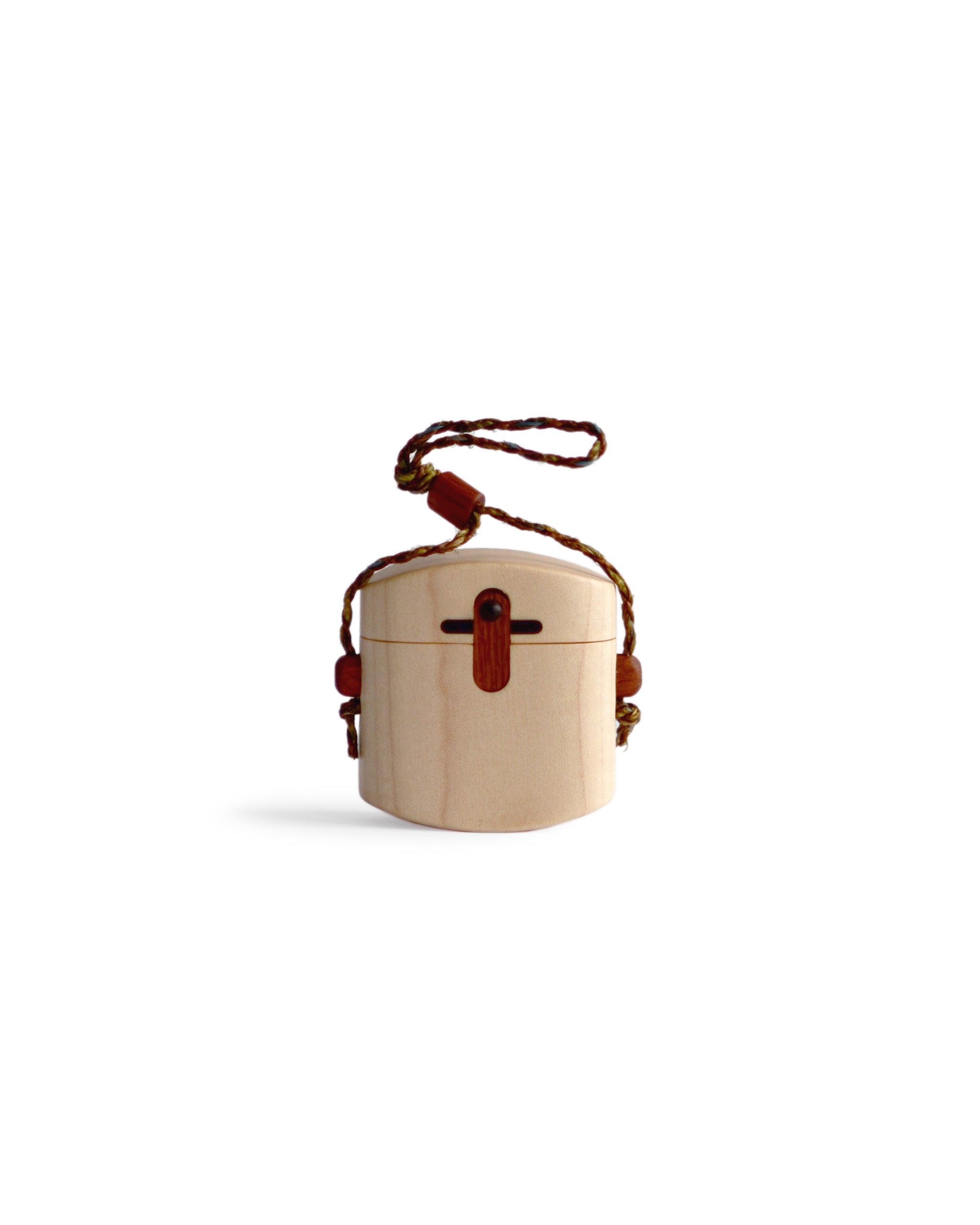 Silhouetted image of maple pill case with cord by Norio Tanno against white background.