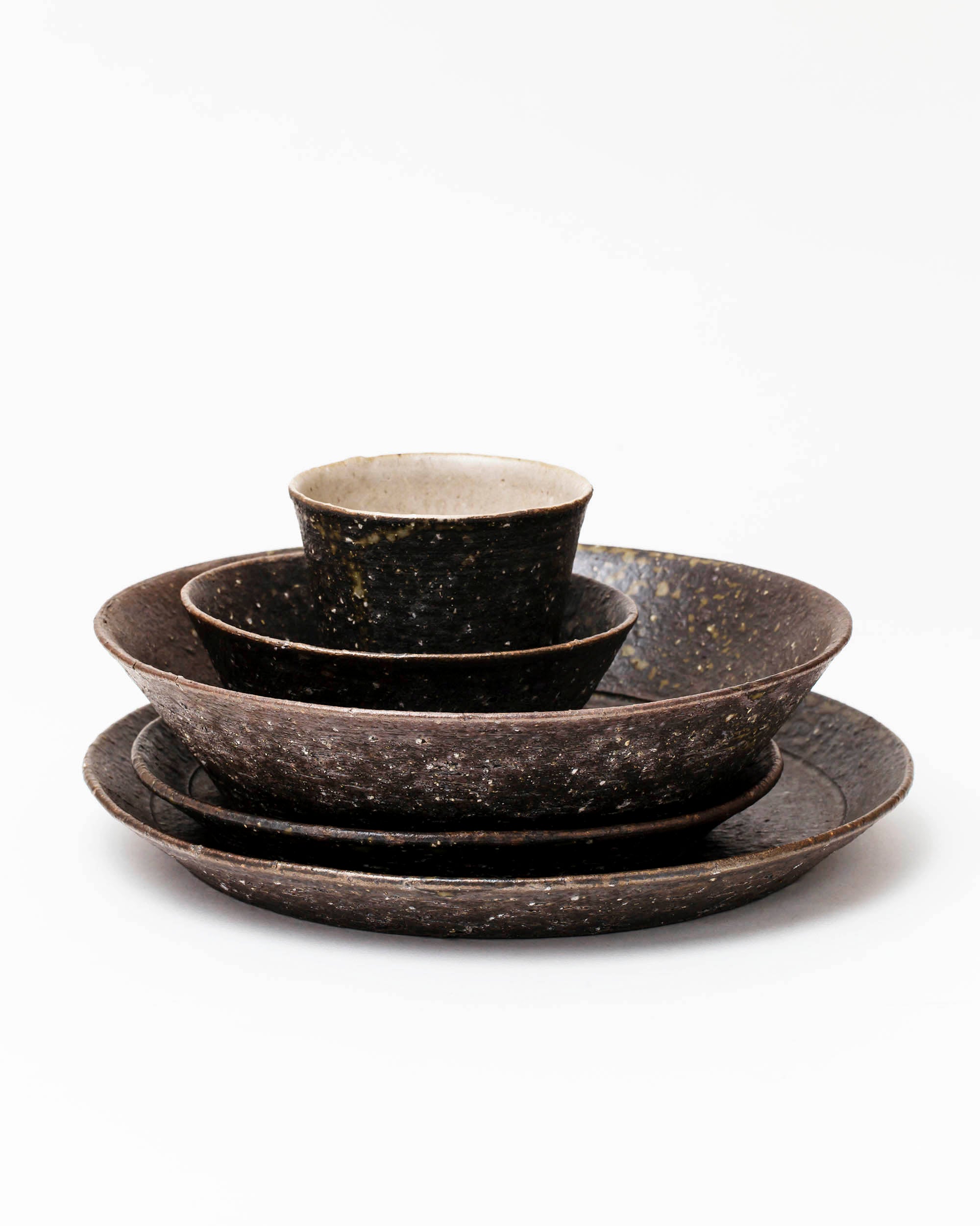 A stack of brown textured tableware stacked on top of each other. They are on a white background.