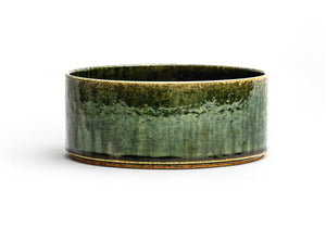 Silhouetted image of ceramic medium oribe bowl with deep green glaze by Time and Style against white background. 