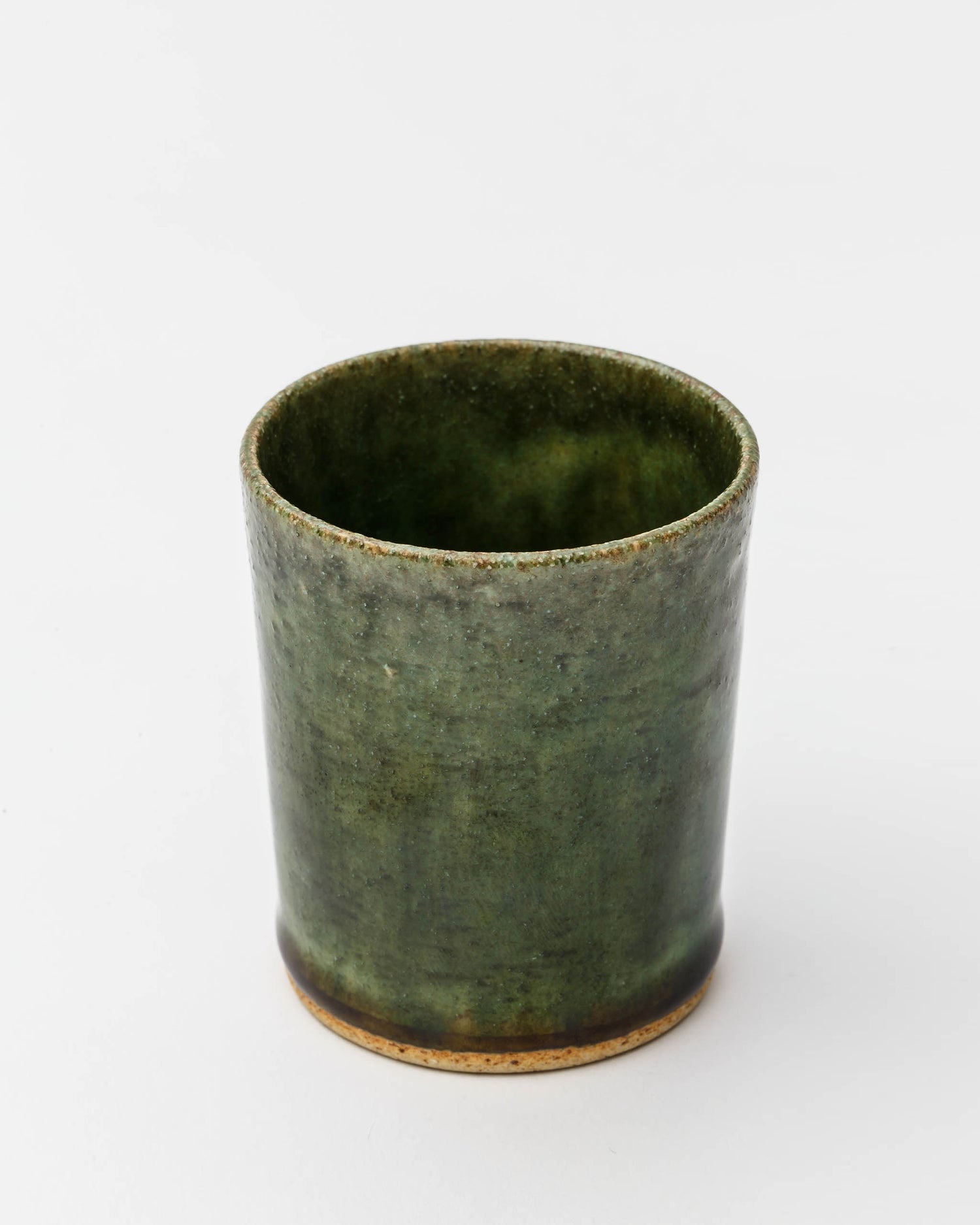 Overhead image looking into ceramic oribe drinking vessel with deep green glaze by Time and Style against white-gray background.