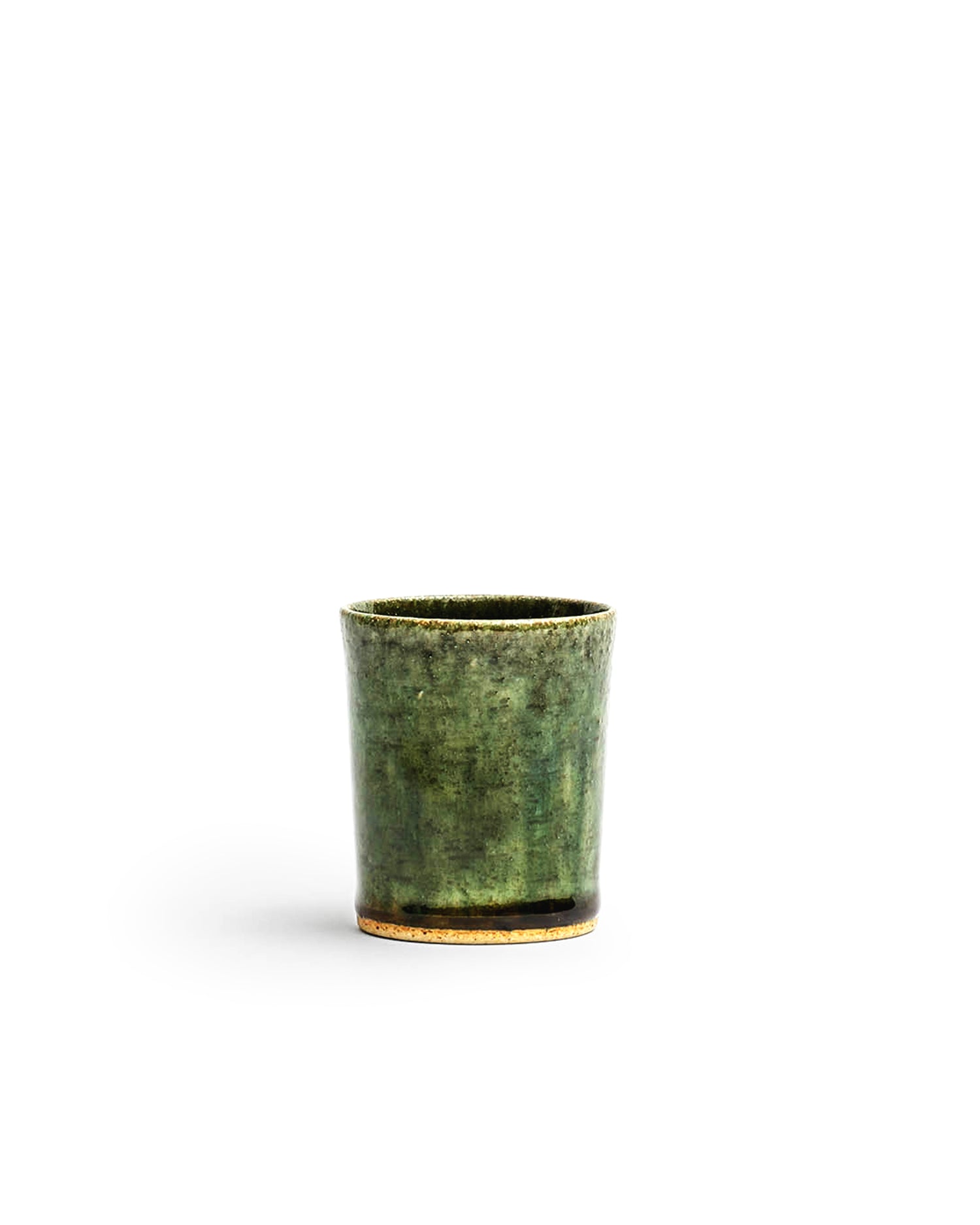 Silhouetted image of ceramic oribe drinking vessel with deep green glaze by Time and Style against white background.