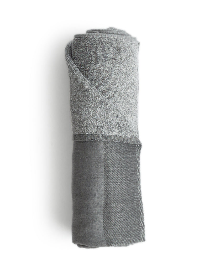 Body size zen charcoal towel rolled up silhouetted against white background.