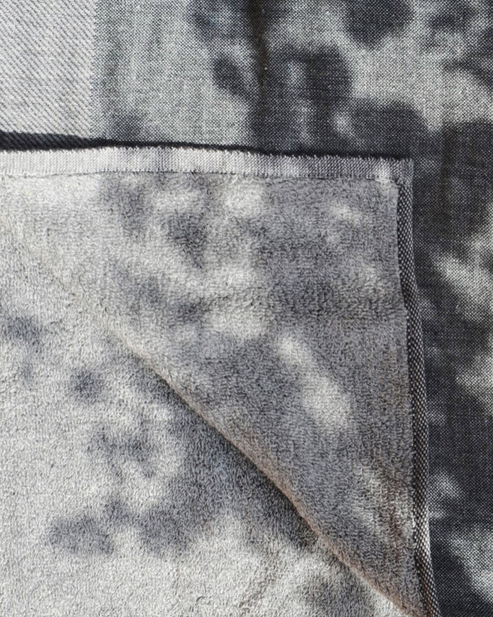 Corner of the zen charcoal towel is folded to show both gauze and terry sides of the towel.