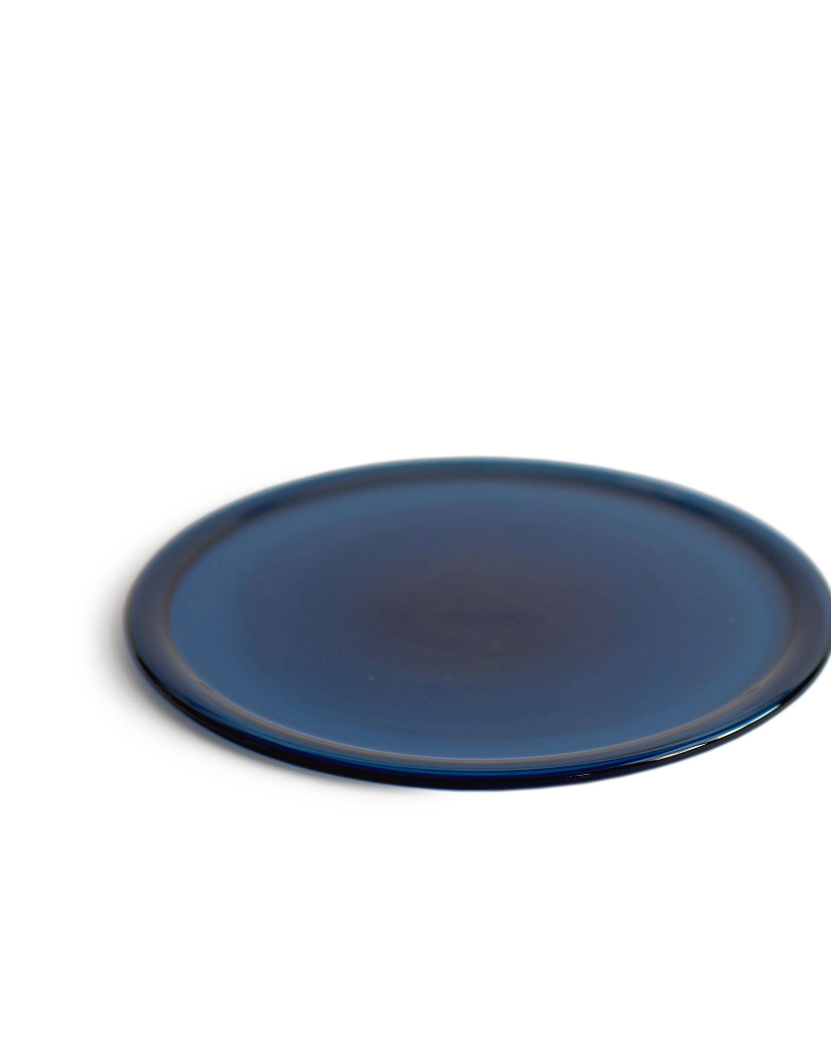 Silhouetted reclaimed blue folded rim plate in dark blue against white background. 