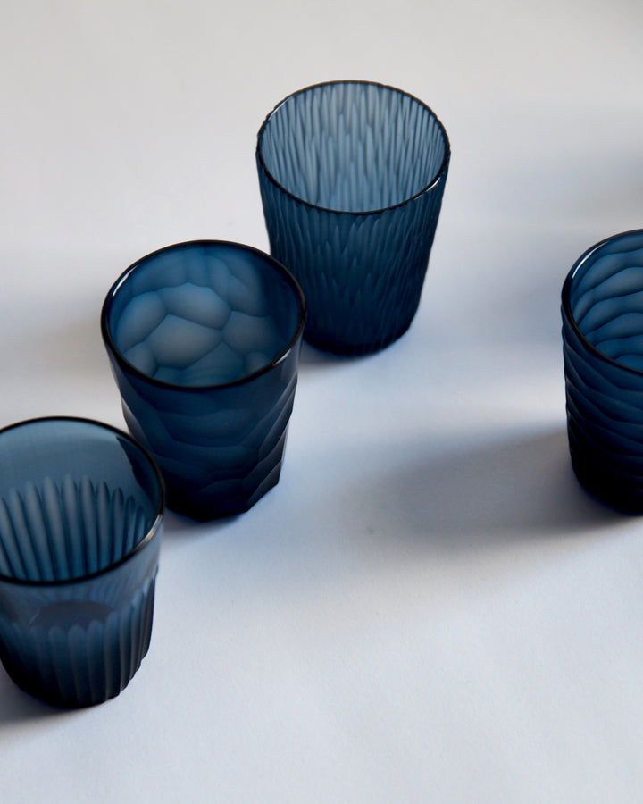 Cropped image of four cups, each with unique carved patterns, placed randomly. 