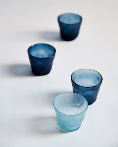 Top view of four reclaimed blue mini choko glasses in different shades randomly placed.