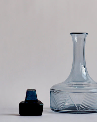 Glass stopper is placed on the left of the reclaimed blue whiskey decanter.