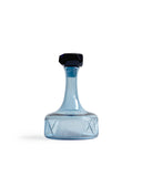 Silhouetted reclaimed blue whiskey decanter against white background.