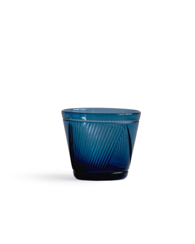 Silhouetted dark blue reclaimed blue whiskey glass against white background.