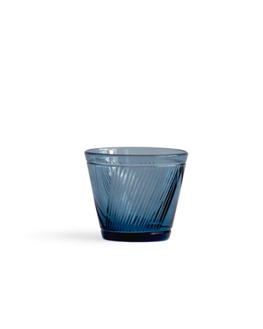 Silhouetted blue reclaimed blue whiskey glass against white background.