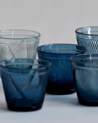Cropped detail view of five reclaimed blue whiskey glasses close together, overlapping. 