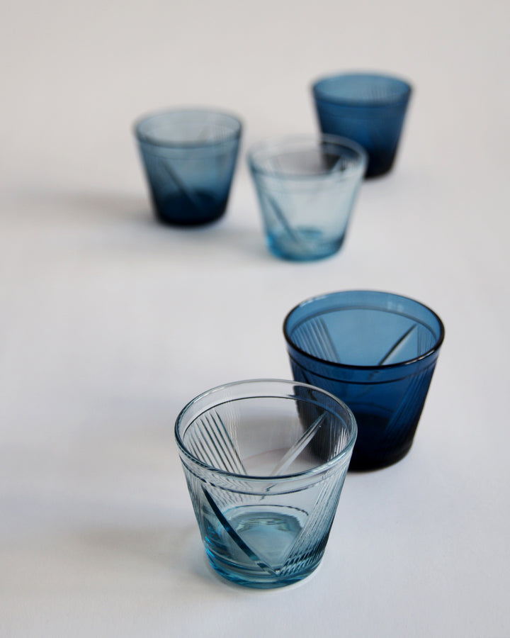 Randomly placed five reclaimed blue whiskey glasses. Each glass is in different shade of blue. 