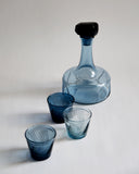 Reclaimed blue decanter is placed along with three reclaimed blue whiskey glasses. Each glass is in different shades of blue.