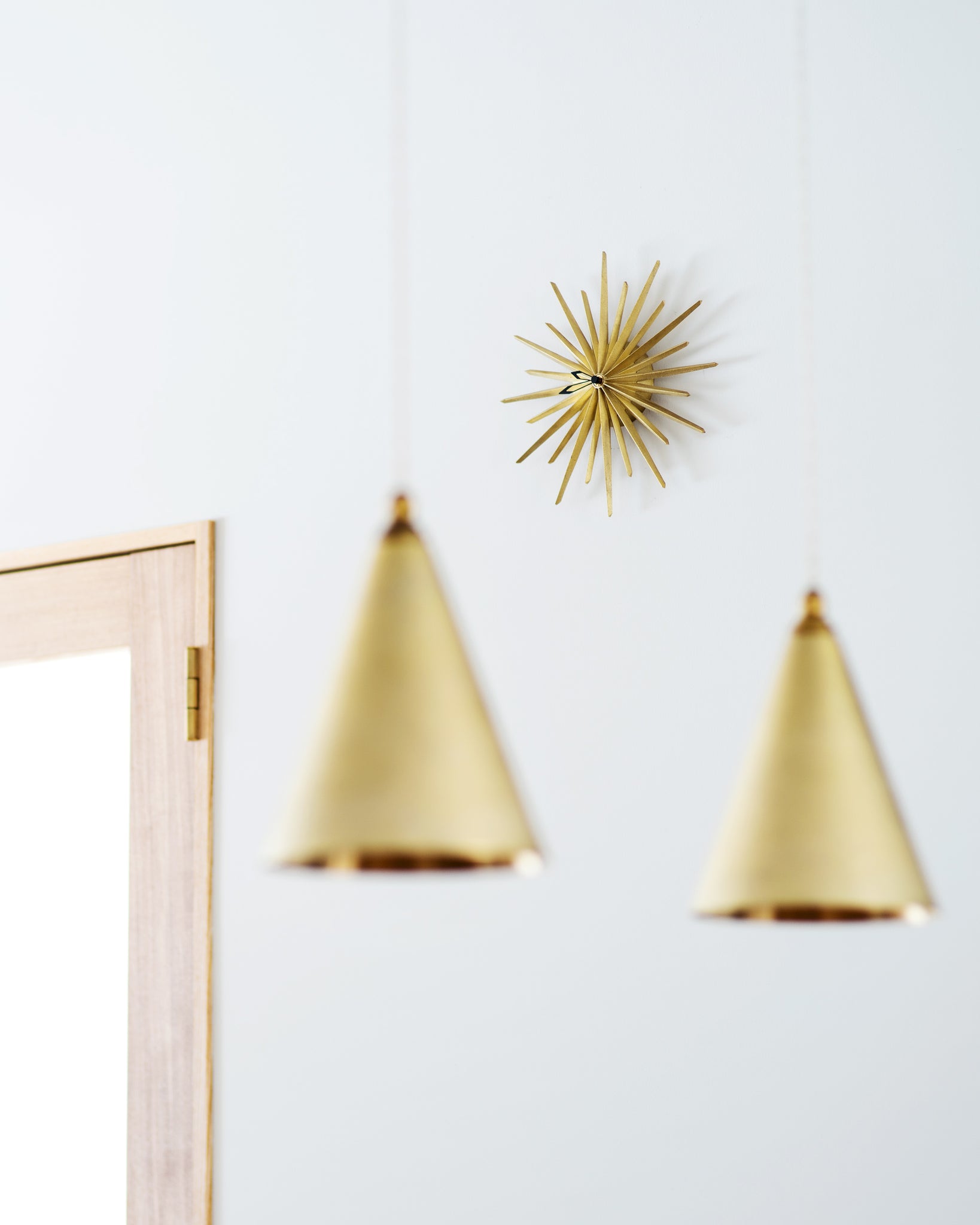 wall hanging brass starburst shape clock hanging on white wall