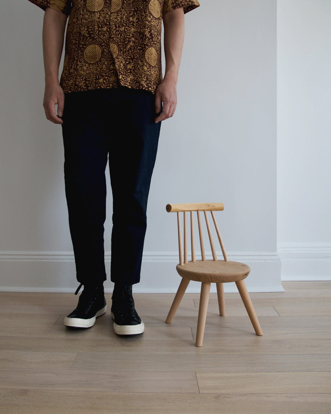 A man in black pants and yellow patterned shirt standing next to the Kinoe Kids Chair.