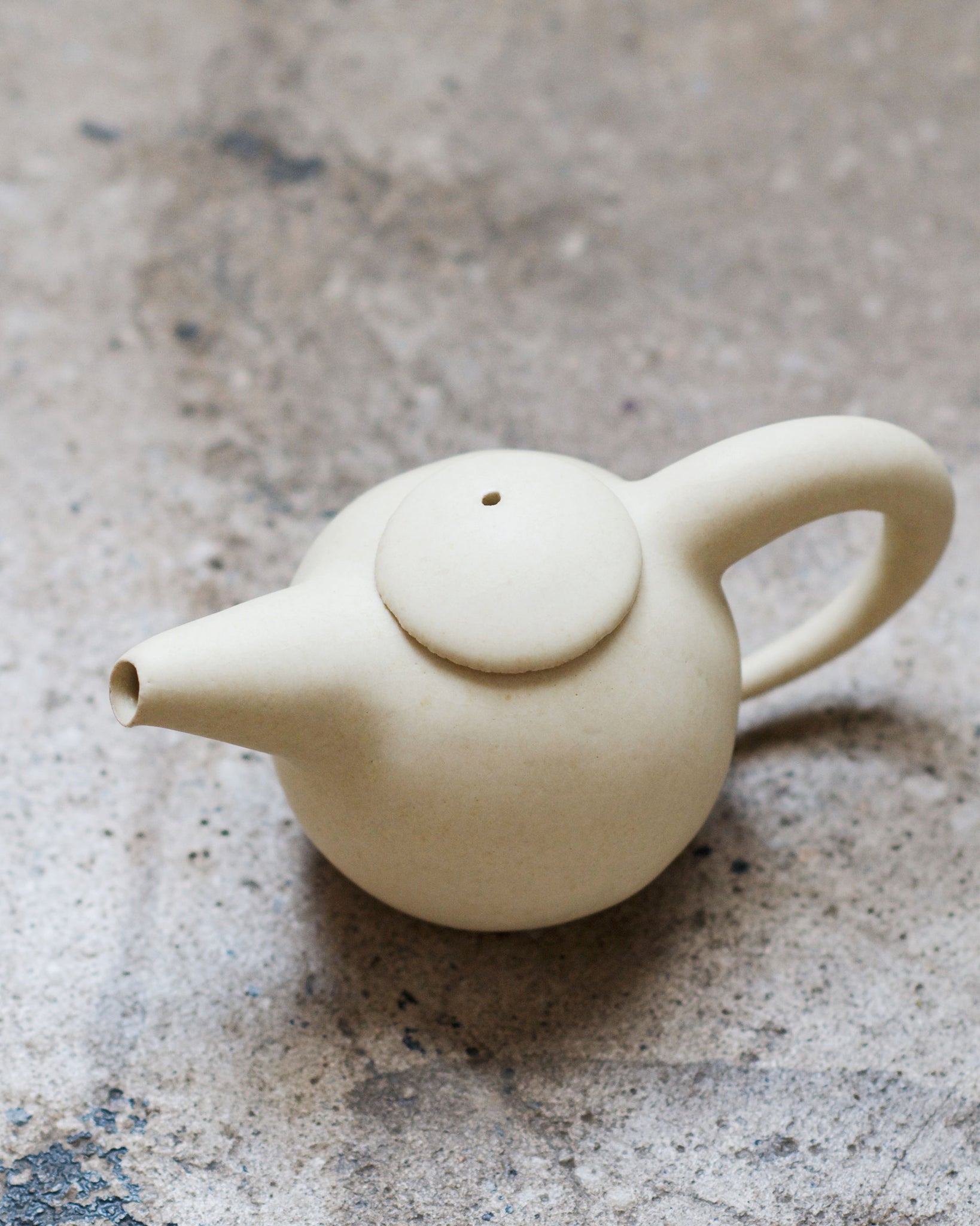 Beige Teapot by Keisuke Iwata against concrete backdrop