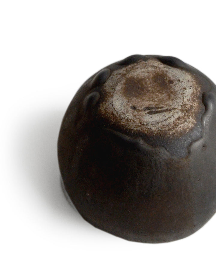 Detail of round black ceramic pod cup handcrafted by Keisuke Iwata against white background