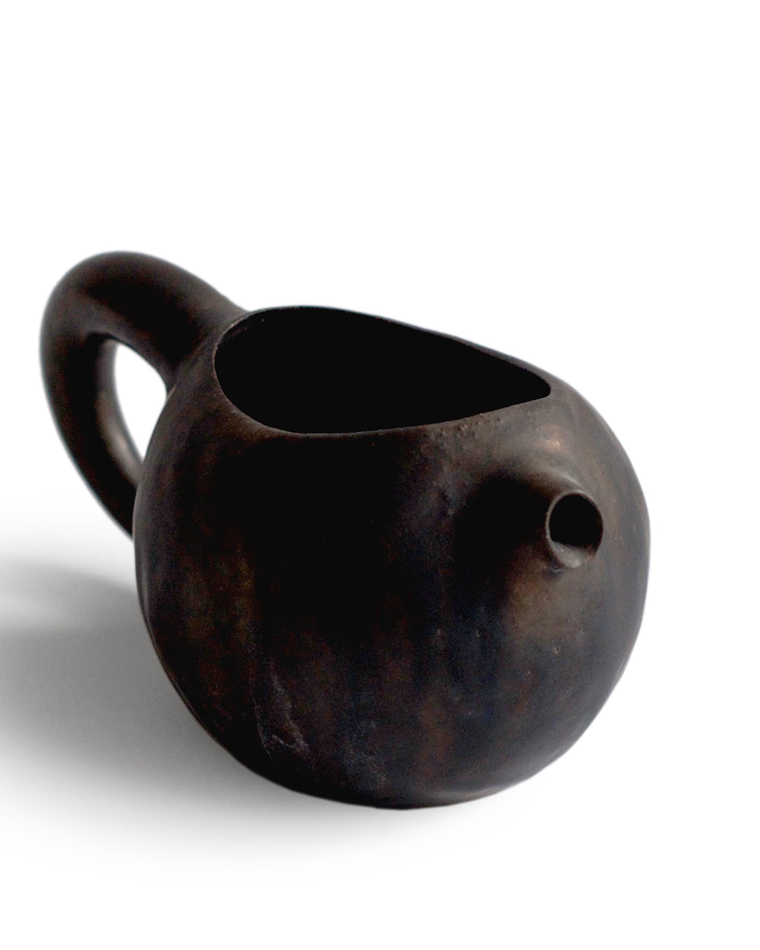 Silhouetted black katakuchi with handle at an angle against white background. 