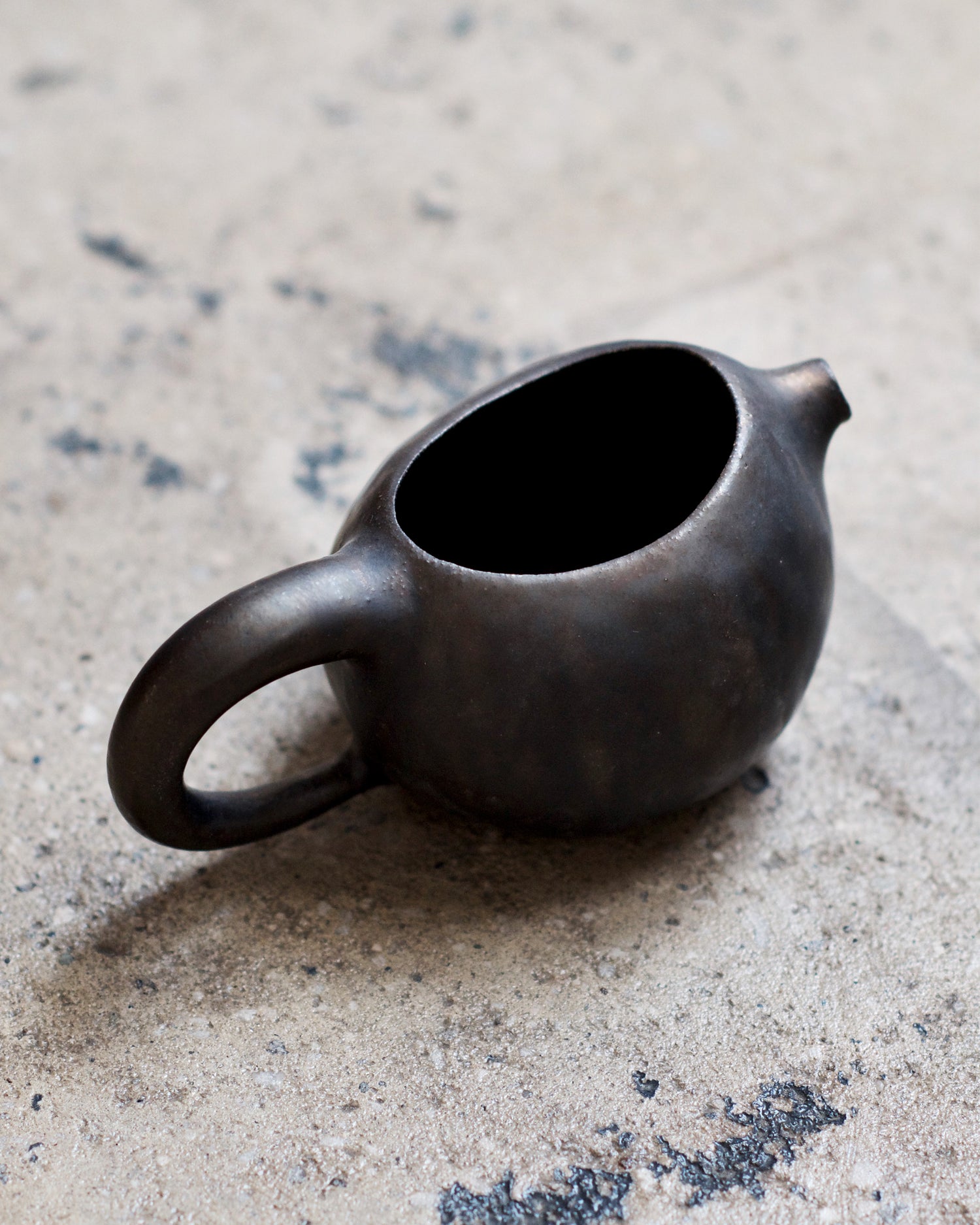 Top view of the katakuchi with handle sitting on a textured cement ground.