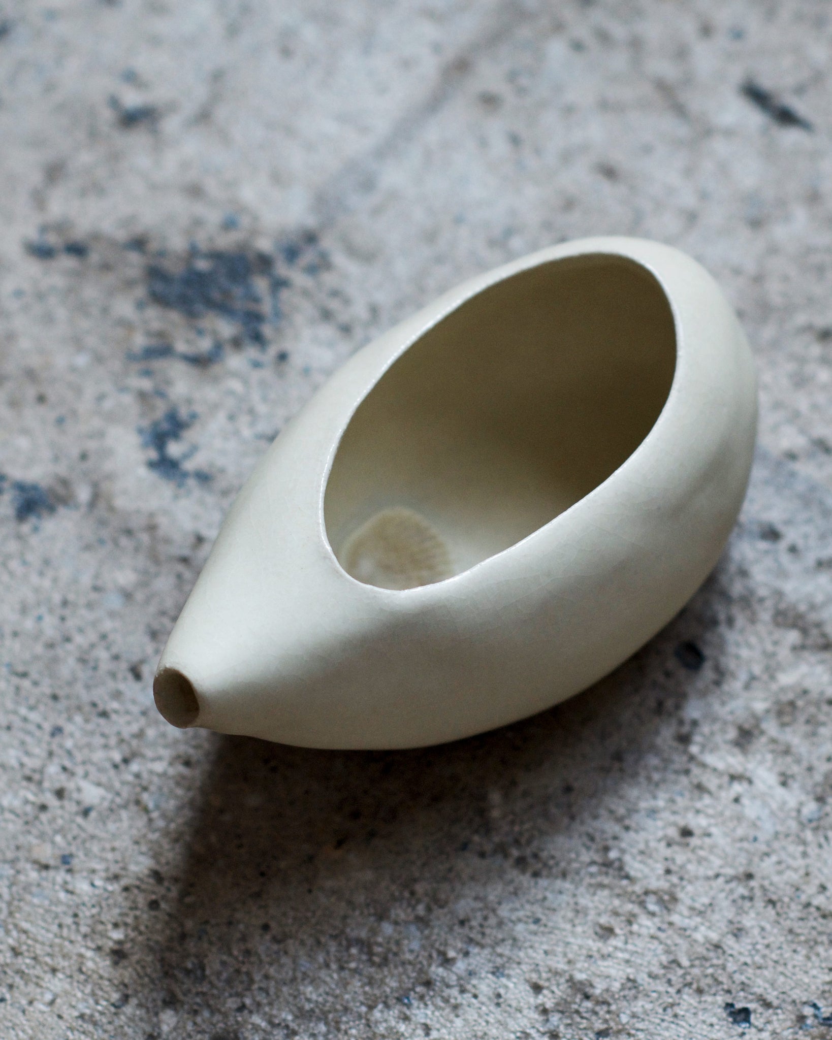 Long beige Katakuchi handcrafted by Keisuke Iwata against concrete backdrop
