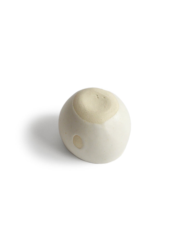 Unglazed bottom of round white ceramic cup handcrafted by Keisuke Iwata against white background