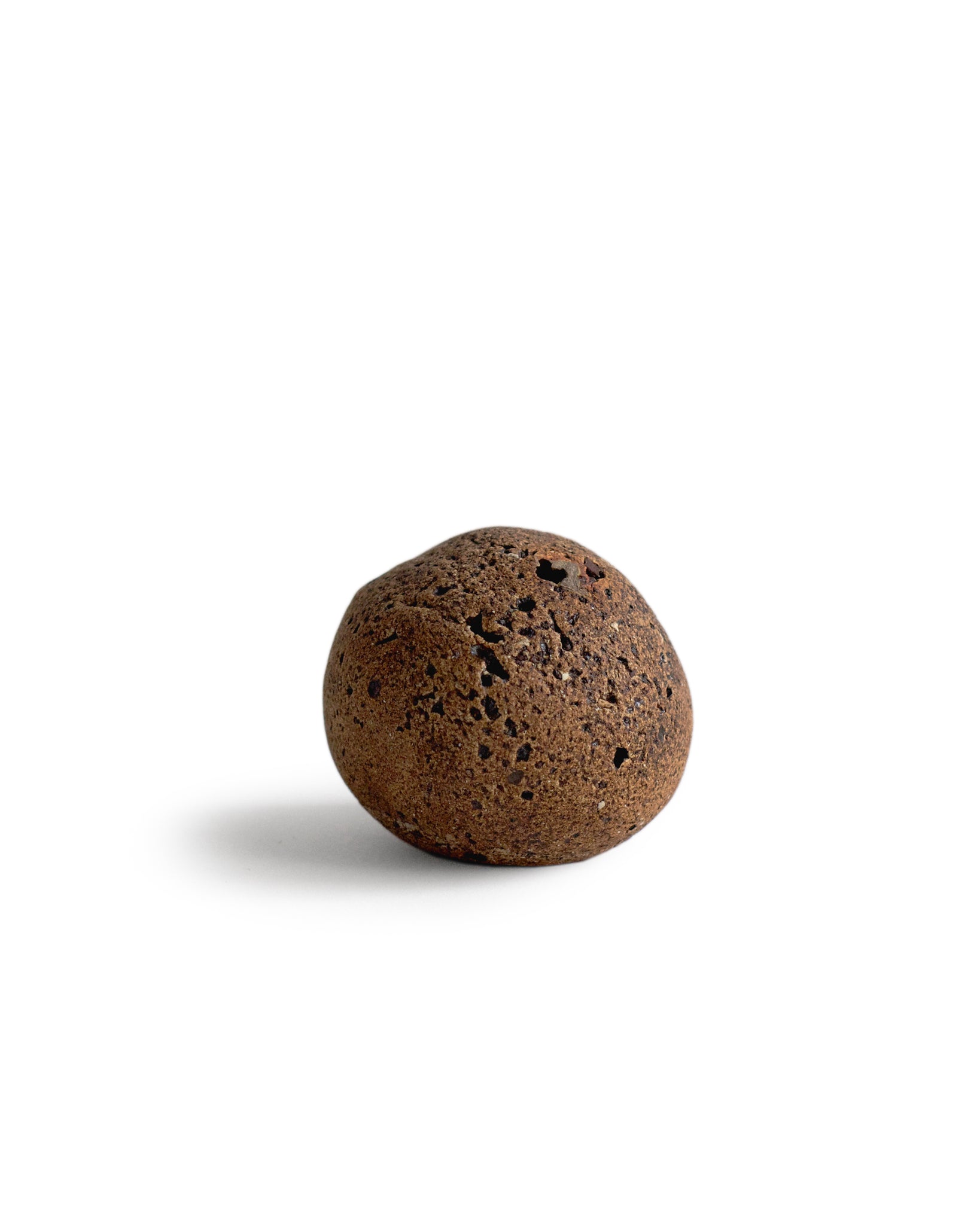 Handcrafted orange stone shaped vase by Keisuke Iwata silhouetted against white background