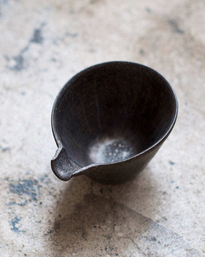 Top view of the black tapered katakuchi on a cement floor.