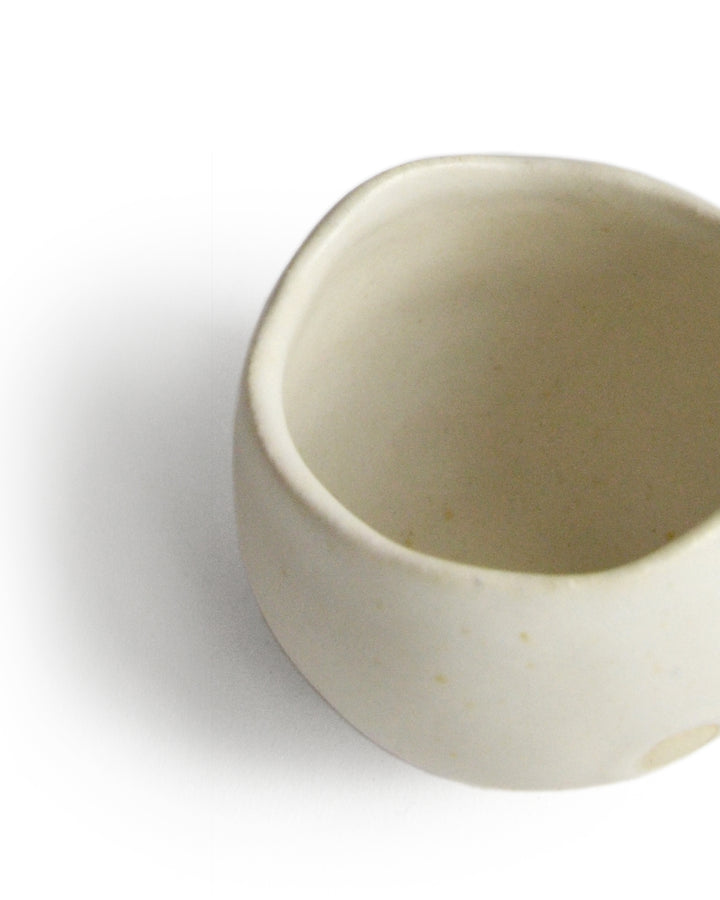 Detail of round white ceramic cup handcrafted by Keisuke Iwata against white background