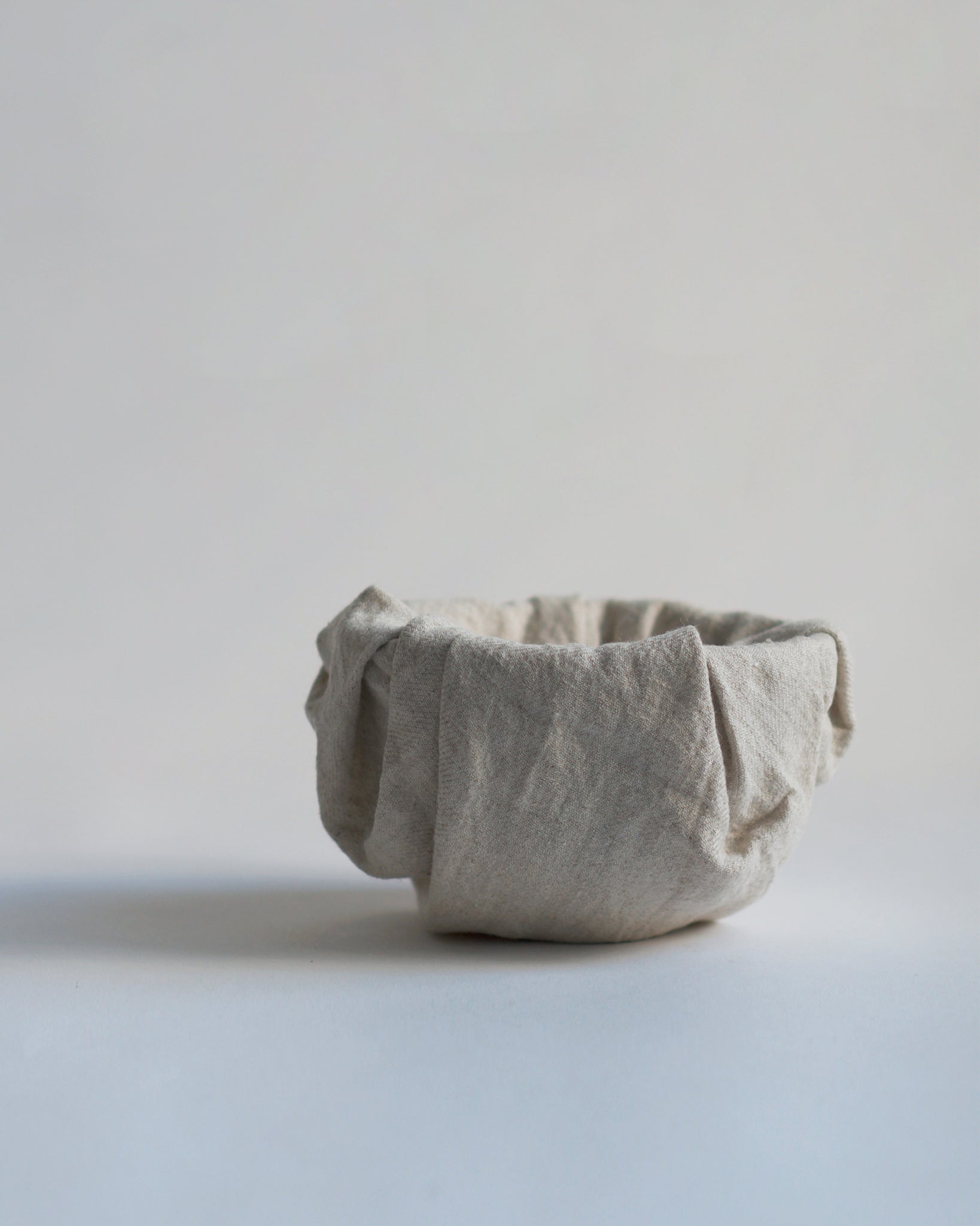 Gold Chawan IV wrapped in cloth against gray background.