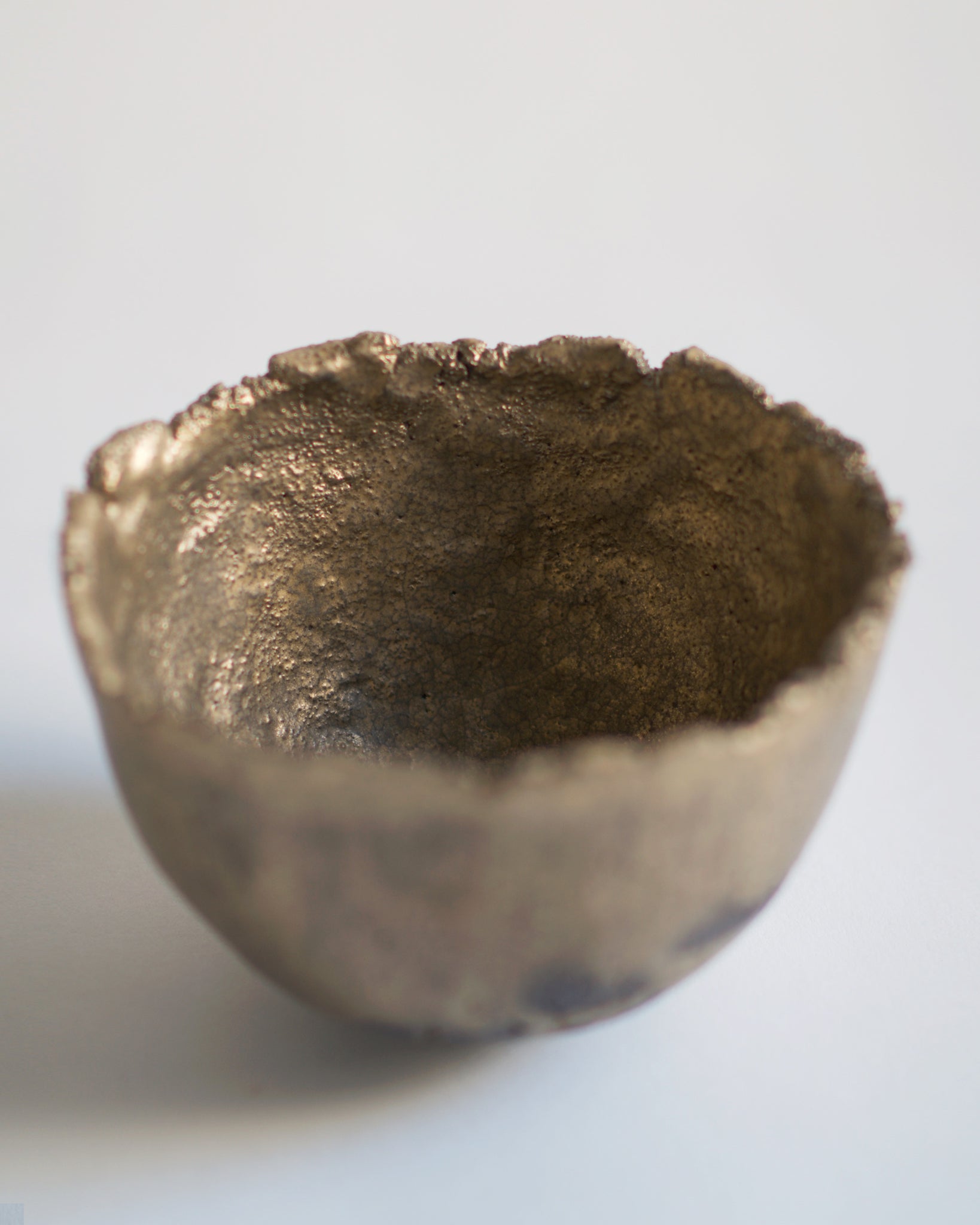 Detailed Gold Chawan IV silhouetted against gray background.