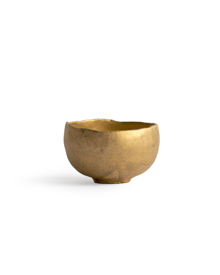 Gold Chawan IX silhouetted against white background.