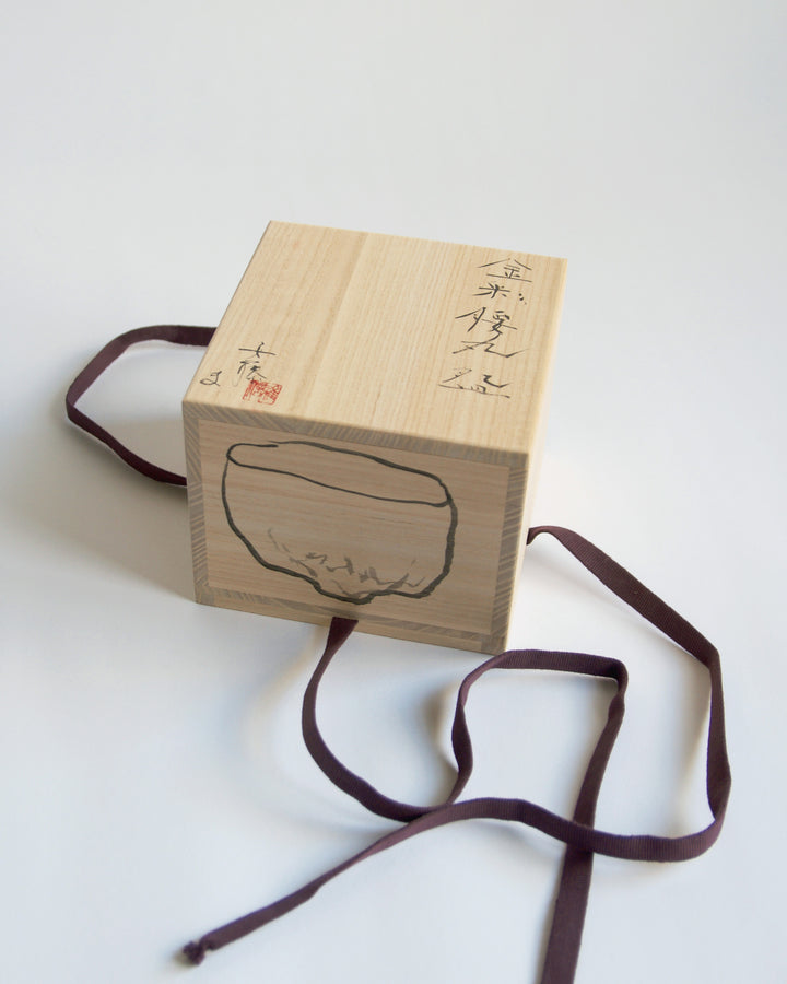 A top view of the wood box for the Gold Chawan VI. Masanobu Ando's calligraphy and drawing of the piece is shown.