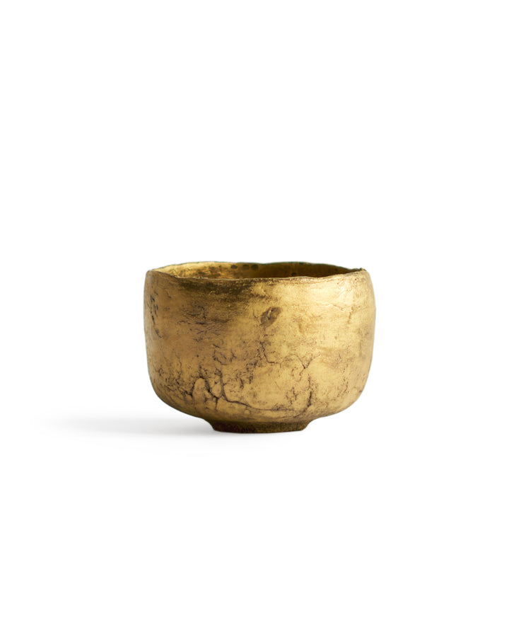 Gold Chawan VI silhouetted against white background.