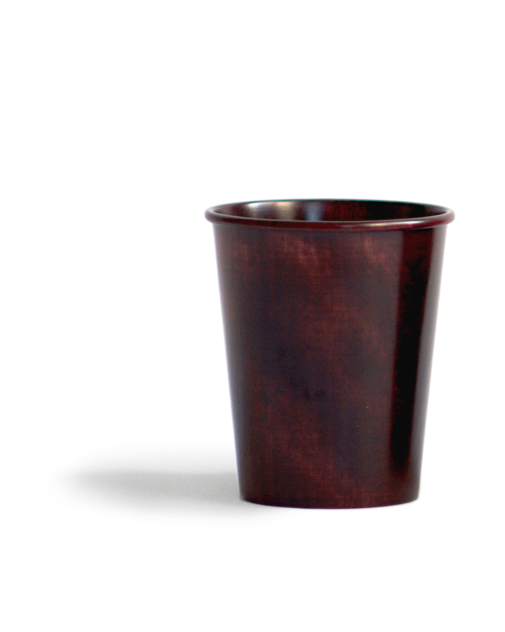 Red urushi wood cup silhouetted against white background.