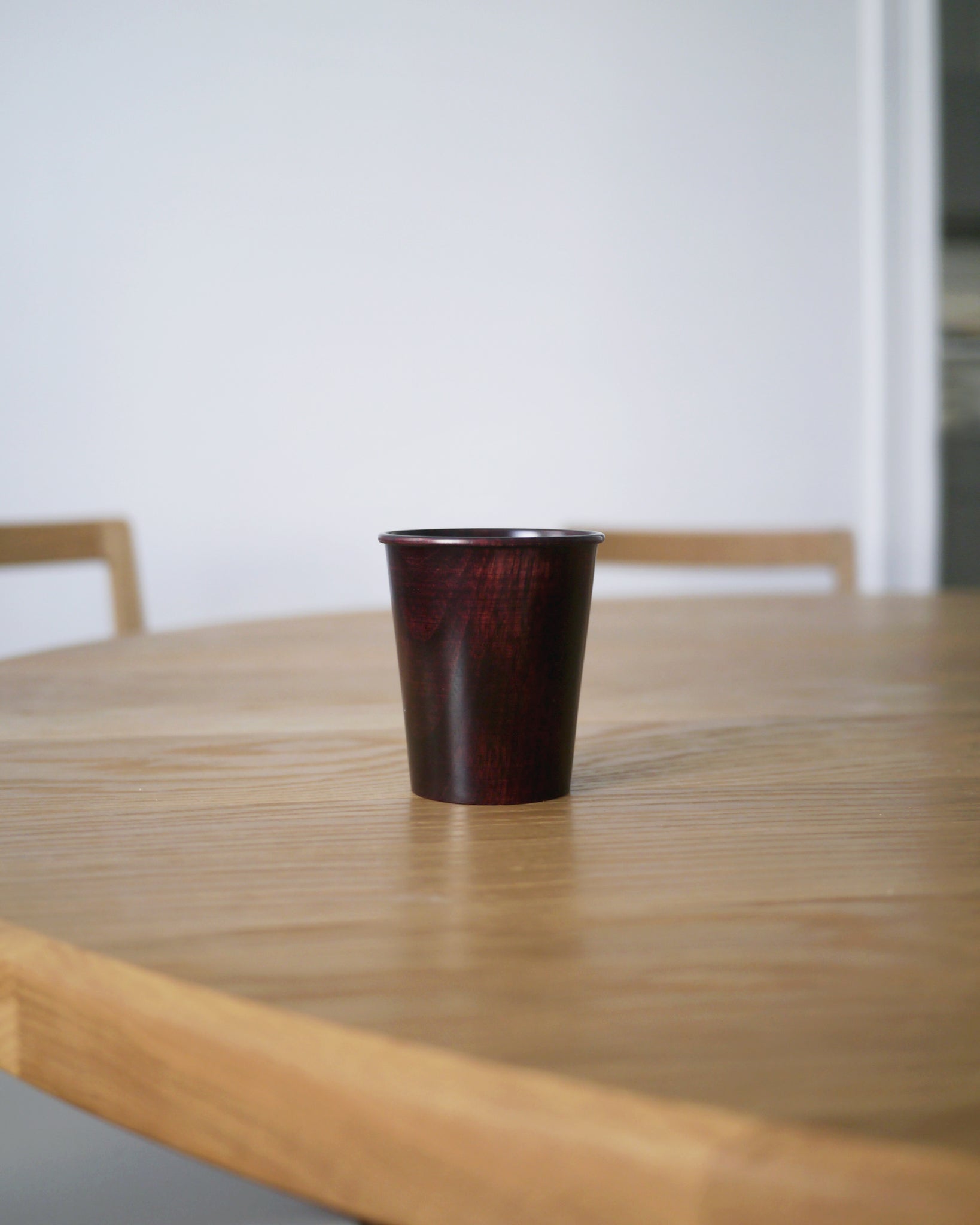 Red urushi wood cup on an oak wood dining table