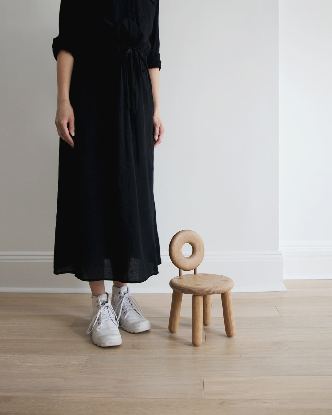 Bialy children's chair next to a woman in black dress standing.  