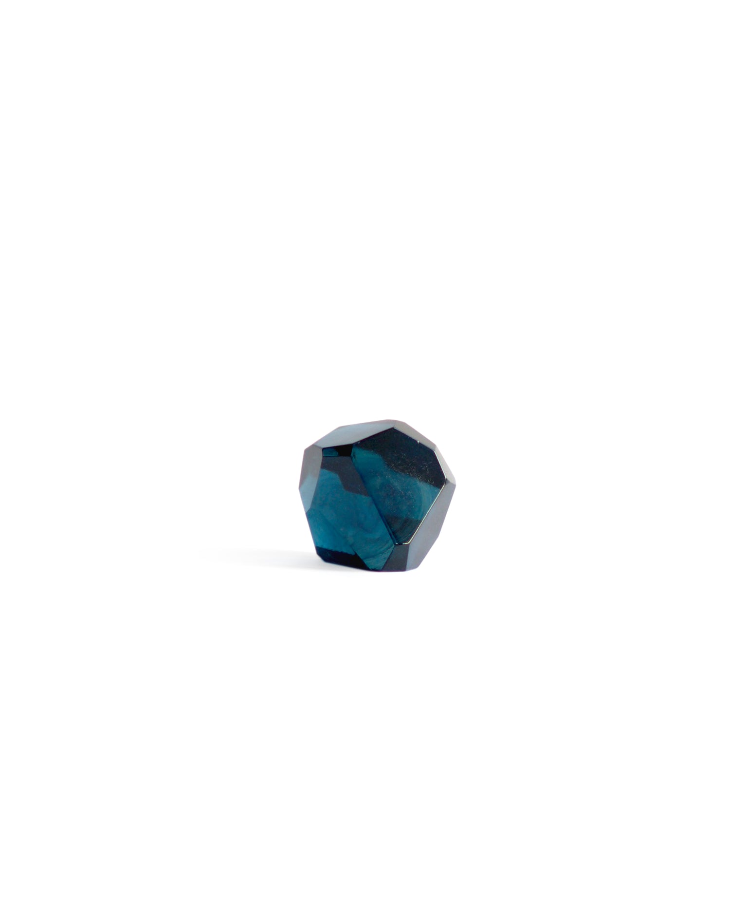Silhouetted dark blue reclaimed blue jewelry cut paperweight against white background. 