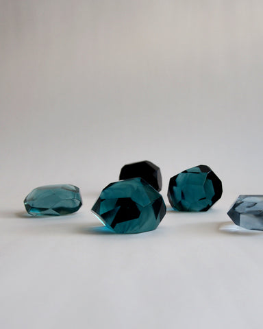 Detailed image of five reclaimed blue jewelry cut paperweights randomly in a row. Each paperweight is of different shades of blue.