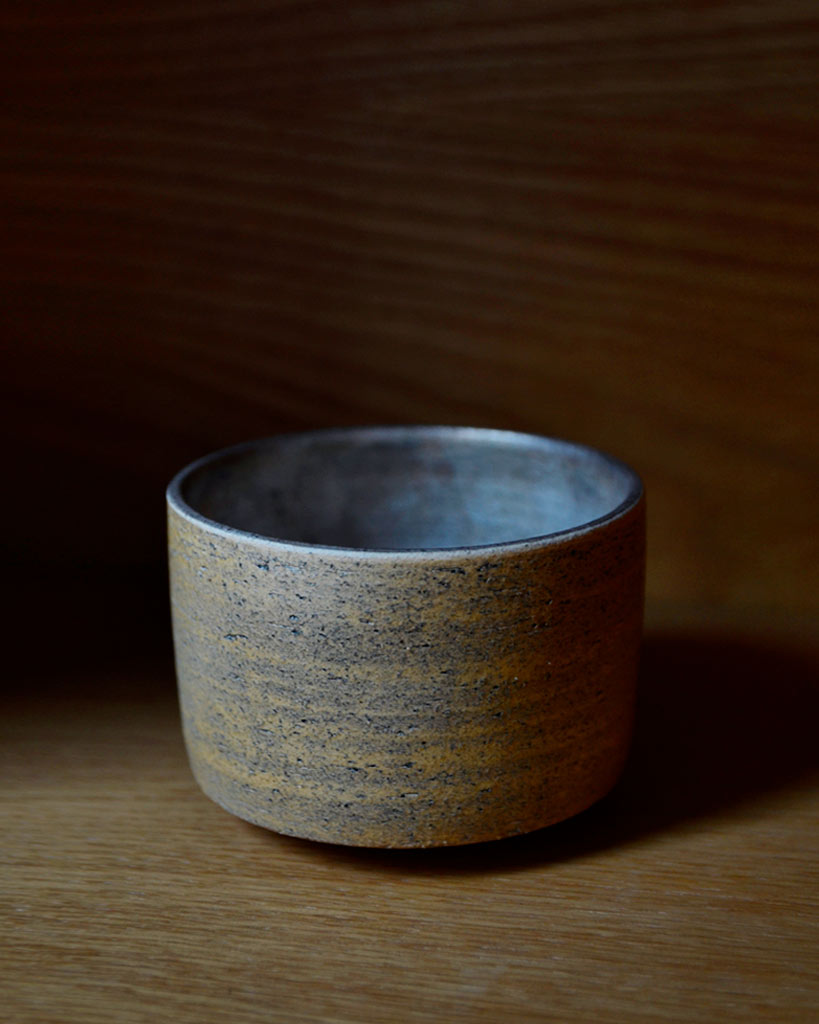 Uchugin silver matcha bowl is placed on top of a oak wood shelf.