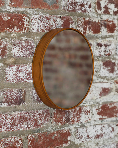 Ayous wood round mirror hanging against exposed brick wall